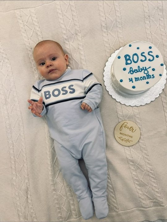 Maren katër muajsh me pizhamet 'BOSS' pranë tortës blu