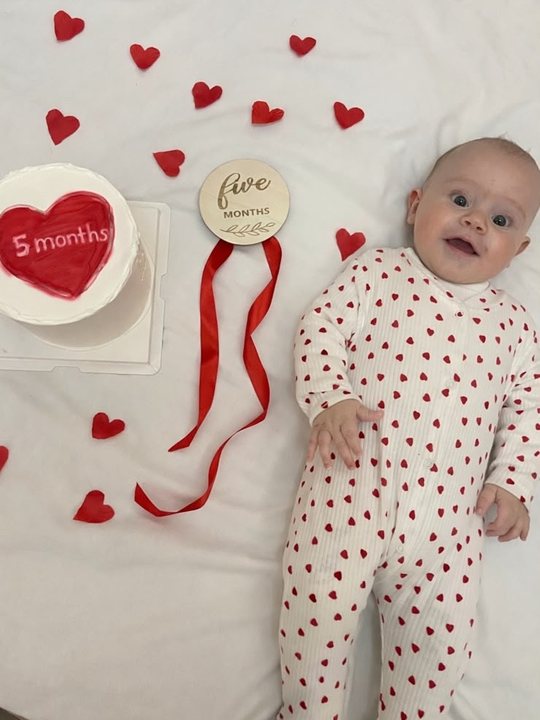 Maren pesë muajsh mes zemrave të kuqe me tortën në formë zemre